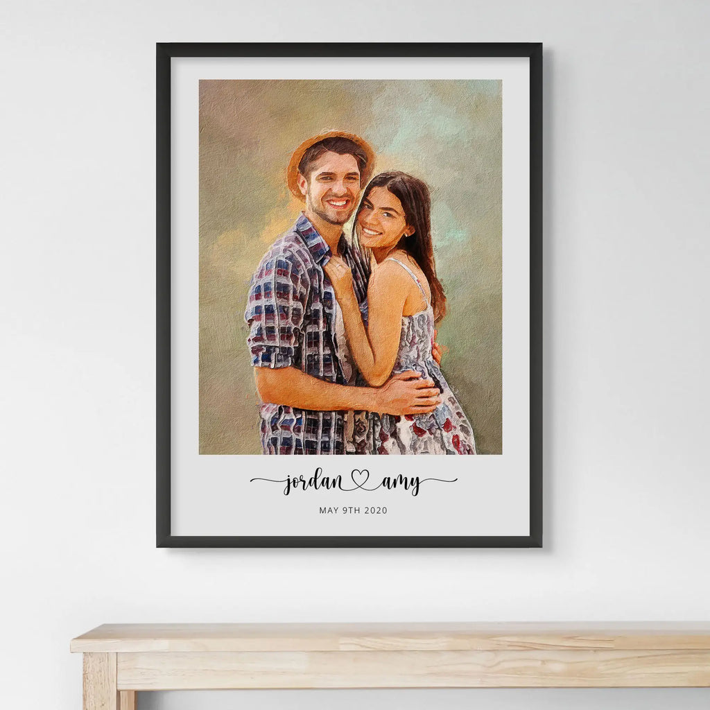 Oil-style portrait of a smiling couple, the man in a straw hat, in a black frame above a light wood table