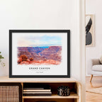 Watercolor-style portrait of the Grand Canyon, framed in black and leaning on a wooden sideboard