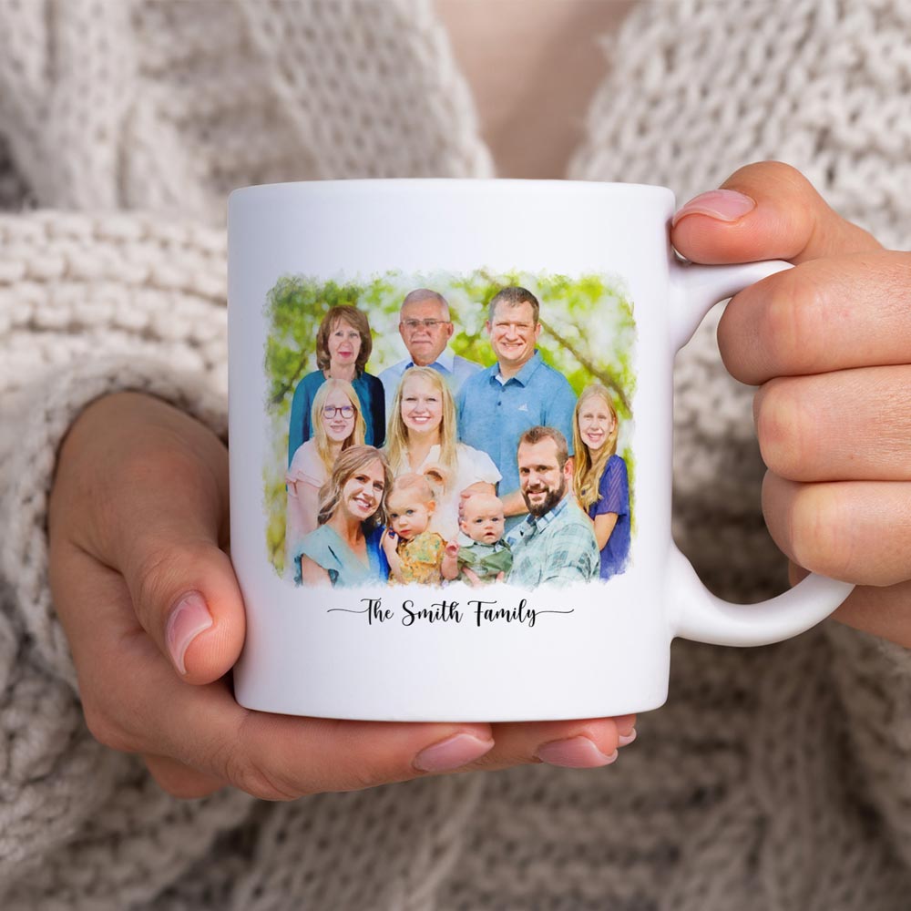 White mug printed with a watercolor-style portrait of a large family and 'The Smith Family', held in two hands
